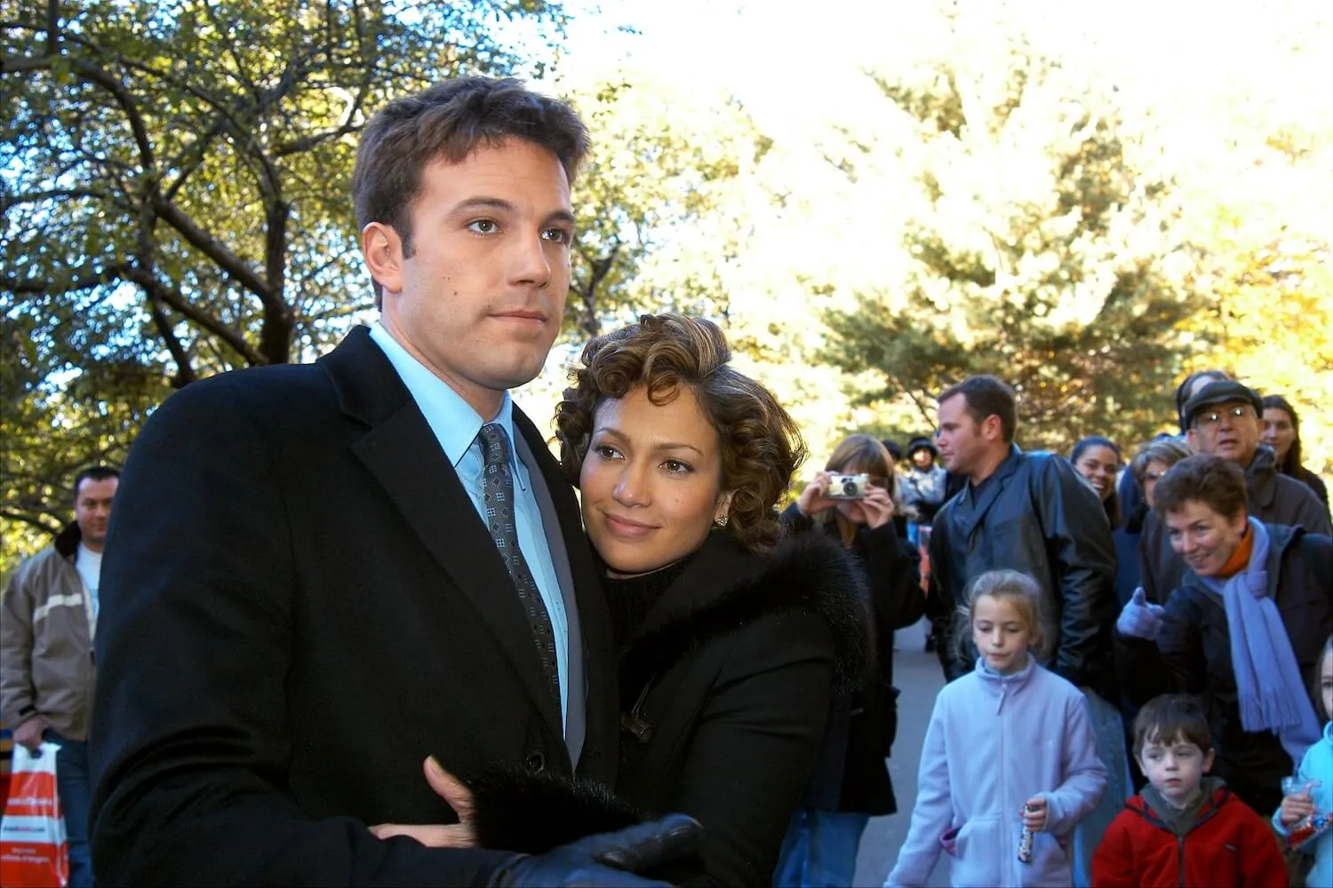 Jennifer Lopez in a coat embracing Ben Affleck, who's wearing a suit, in an off-camera love scene in Central Park