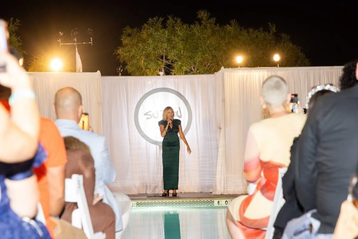 Wearing a green dress, Sutton Stracke speaks during the Fashion show