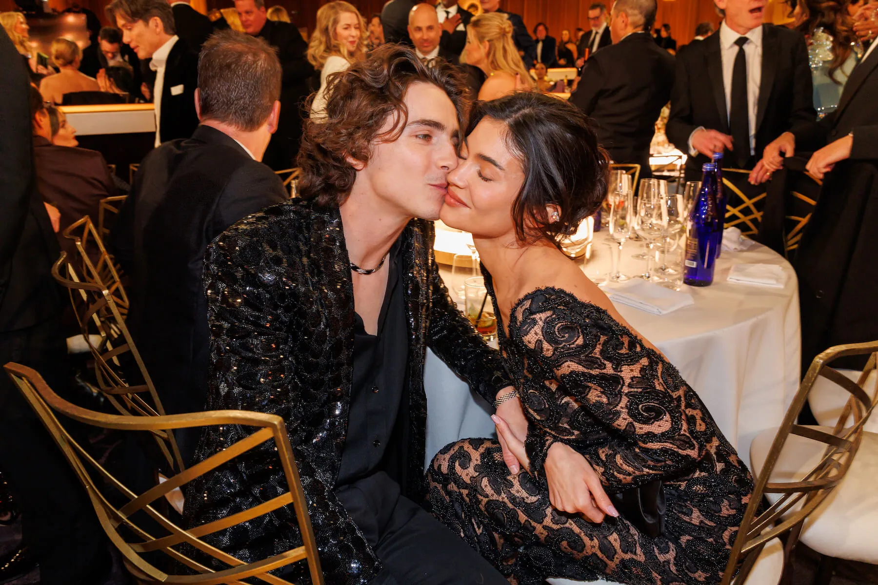 Timothée Chalamet kissing Kylie Jenner's cheek while sitting at a table at the 81st Golden Globe Awards